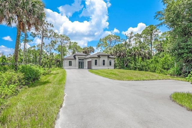 prairie-style home with a front yard, driveway, and stucco siding