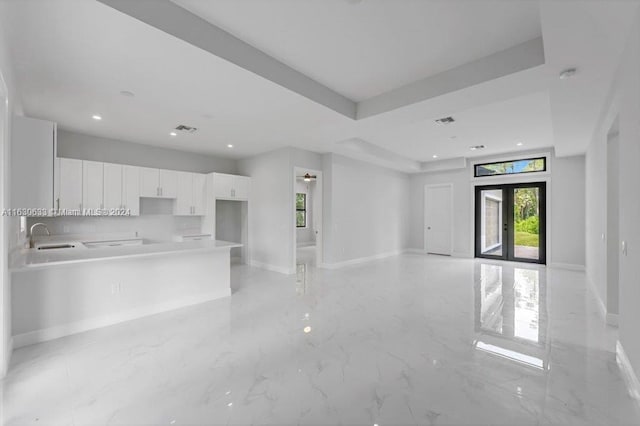 kitchen with visible vents, white cabinets, open floor plan, a tray ceiling, and light countertops