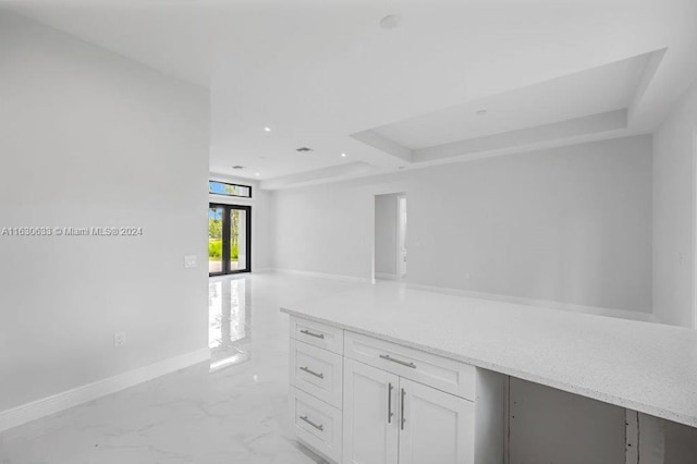 kitchen featuring baseboards, open floor plan, marble finish floor, light countertops, and white cabinets