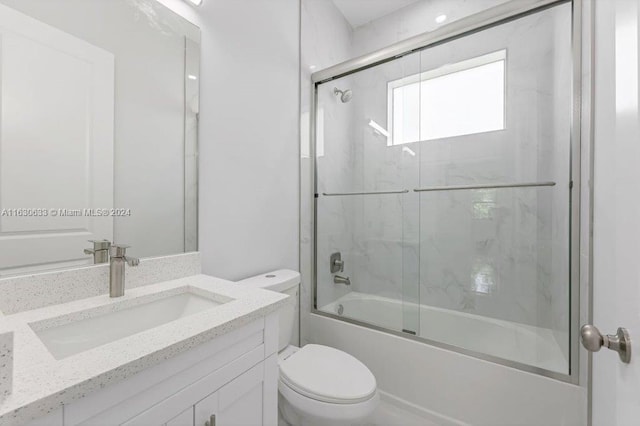 bathroom featuring toilet, bath / shower combo with glass door, and vanity