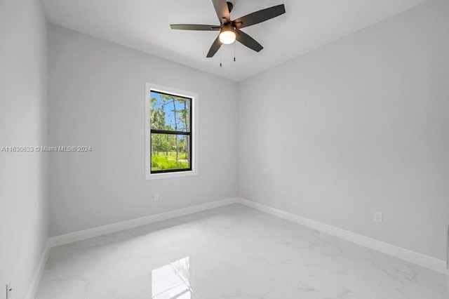 unfurnished room with ceiling fan, marble finish floor, and baseboards