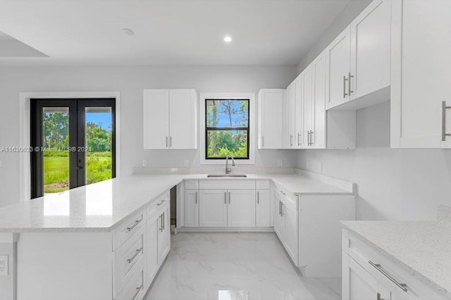 kitchen with white cabinets, light stone countertops, marble finish floor, a sink, and recessed lighting