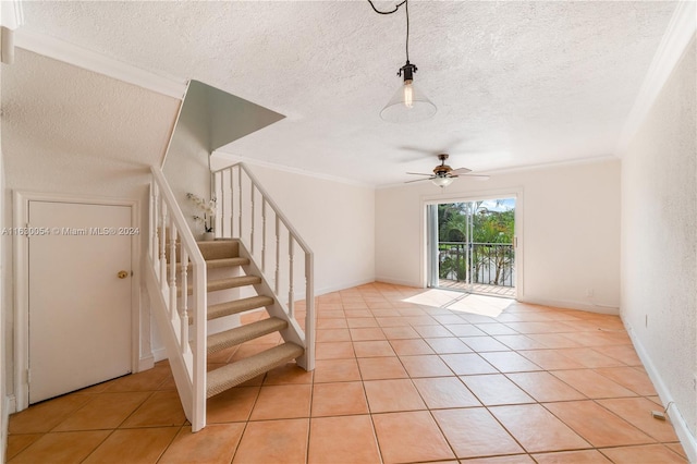 interior space featuring ceiling fan, tile patterned flooring, a textured ceiling, and ornamental molding