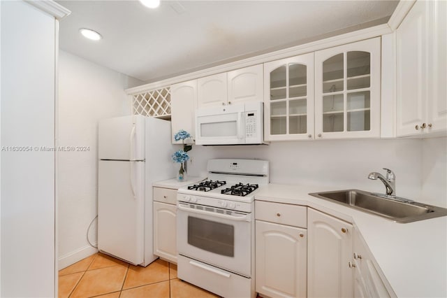 kitchen with white appliances, sink, light tile patterned flooring, and white cabinets