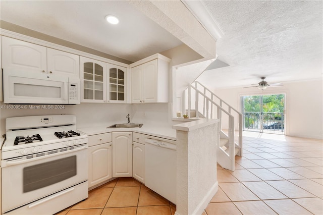 kitchen featuring white cabinets, a textured ceiling, sink, light tile patterned flooring, and white appliances