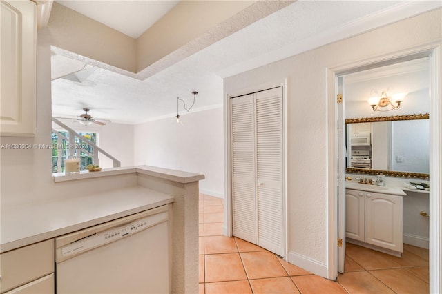 kitchen with light tile patterned flooring, sink, white dishwasher, ceiling fan, and a textured ceiling