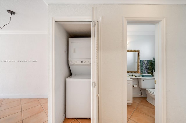 laundry area with stacked washing maching and dryer and light tile patterned floors