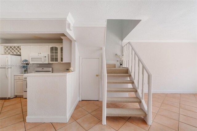 staircase featuring tile patterned flooring, a textured ceiling, and crown molding