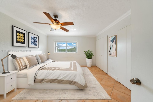 bedroom featuring ornamental molding, a textured ceiling, light tile patterned floors, and ceiling fan