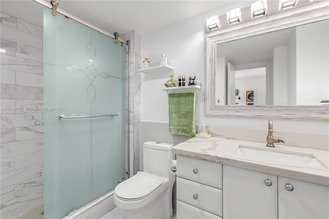 bathroom featuring a shower with door, toilet, and vanity