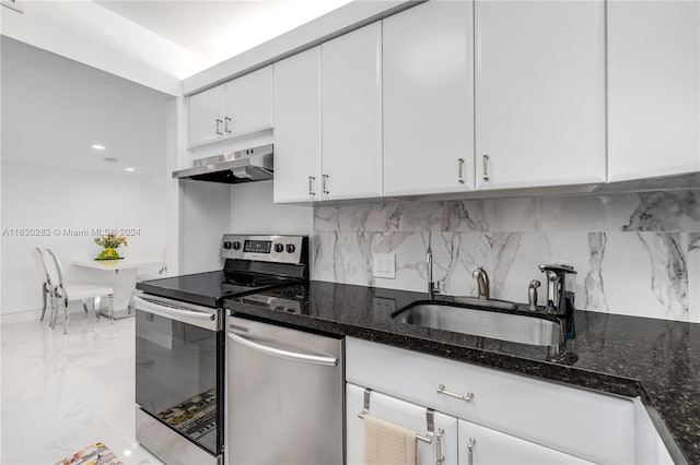 kitchen featuring appliances with stainless steel finishes, tasteful backsplash, sink, dark stone countertops, and white cabinetry