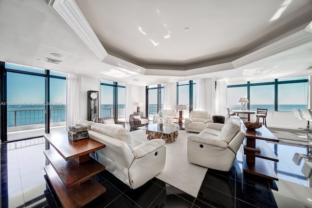 tiled living room with floor to ceiling windows, a water view, ornamental molding, a tray ceiling, and a barn door