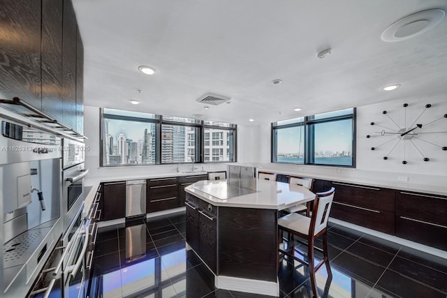 kitchen with dark tile patterned floors, a center island, a wealth of natural light, and a kitchen breakfast bar