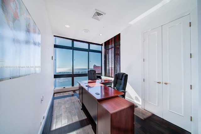 office with dark wood-type flooring, a water view, and floor to ceiling windows