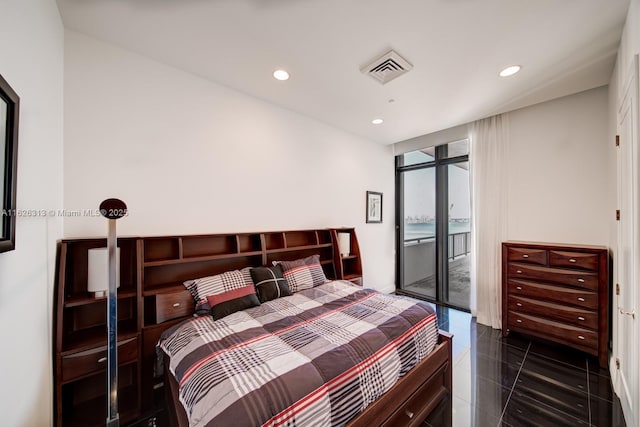 bedroom featuring access to exterior, a wall of windows, and dark tile patterned flooring