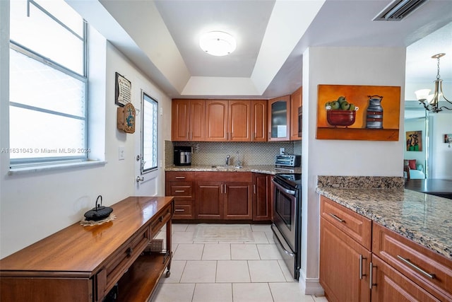 kitchen with light tile patterned flooring, tasteful backsplash, electric range, an inviting chandelier, and dark stone countertops