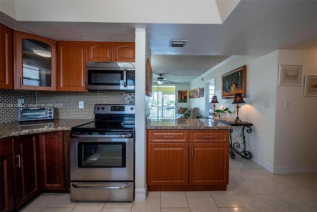 kitchen featuring light tile patterned floors, appliances with stainless steel finishes, stone countertops, and ceiling fan