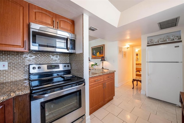 kitchen featuring appliances with stainless steel finishes, light tile patterned flooring, stone countertops, and tasteful backsplash