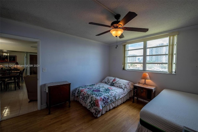 tiled bedroom with a textured ceiling, ceiling fan, and crown molding