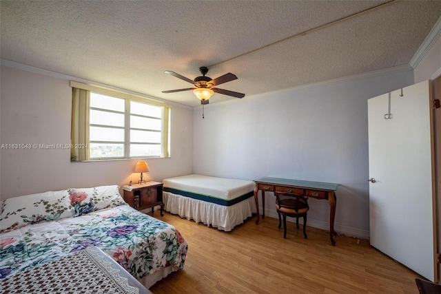 bedroom with light wood-type flooring, ceiling fan, ornamental molding, and a textured ceiling