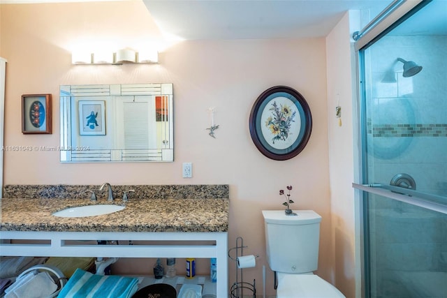 bathroom featuring a shower with shower door, vanity, and toilet