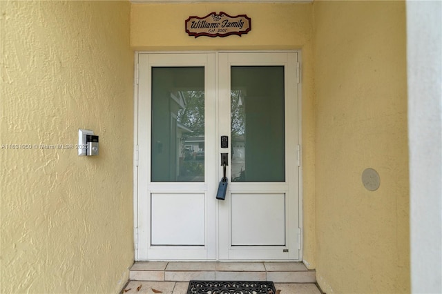 view of exterior entry featuring french doors and stucco siding