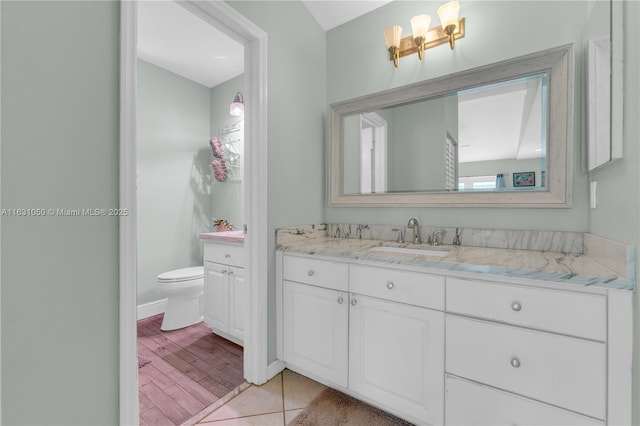 bathroom with baseboards, toilet, wood finished floors, and vanity