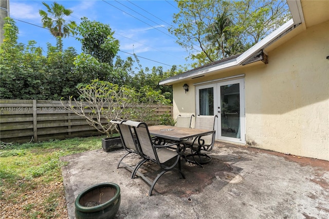 view of patio featuring french doors, outdoor dining area, and fence