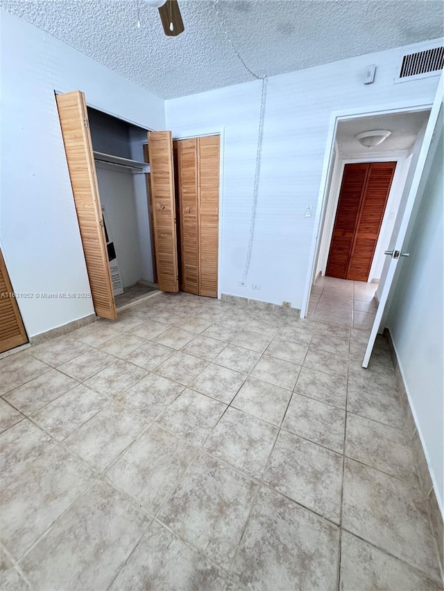 unfurnished bedroom with ceiling fan, tile patterned floors, and a textured ceiling