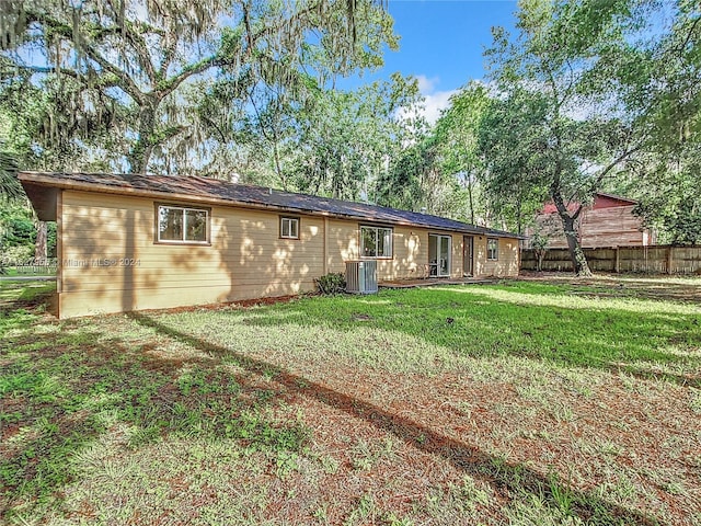 rear view of house with a yard and central AC unit