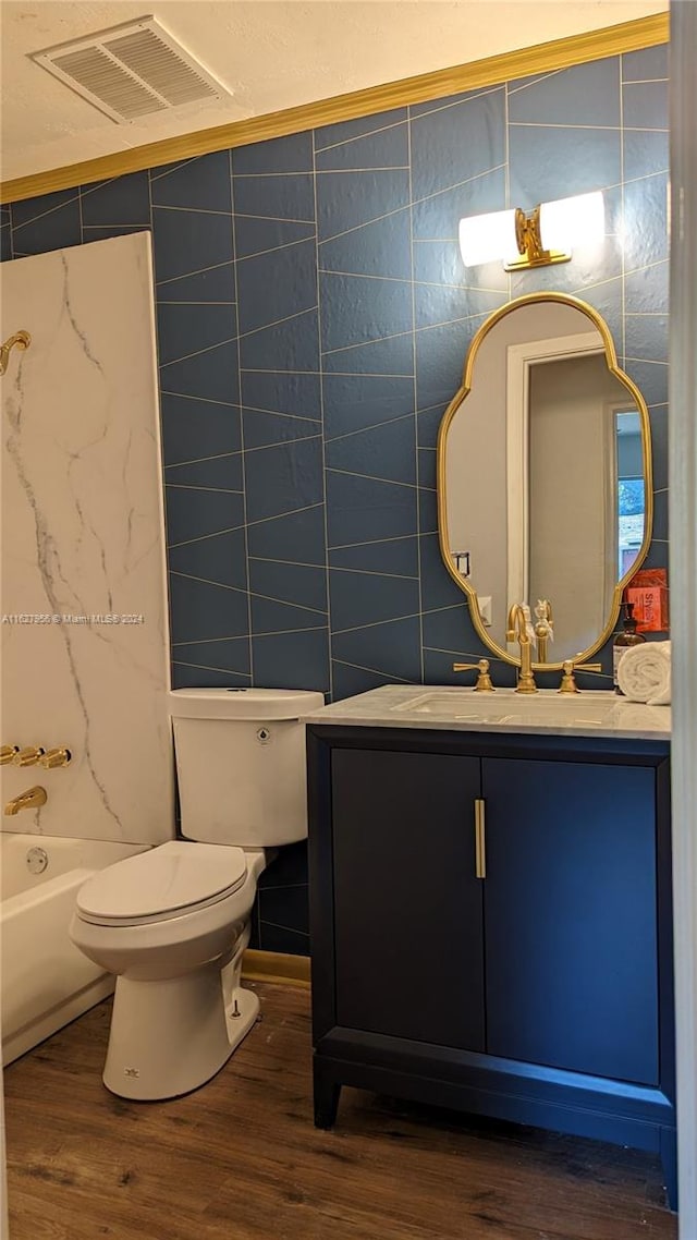 full bathroom with hardwood / wood-style flooring, toilet, vanity, and tile walls