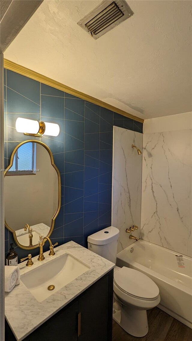 full bathroom featuring vanity, tile walls, hardwood / wood-style flooring, and toilet