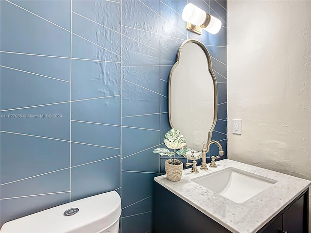 bathroom featuring vanity, tile walls, and toilet