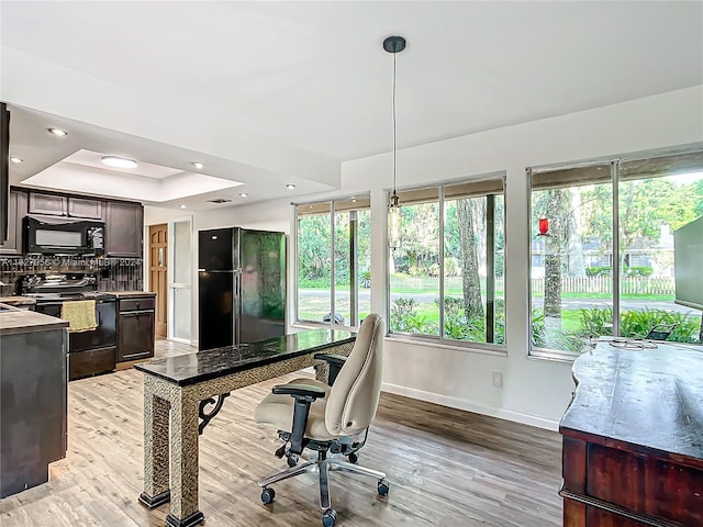 office space featuring light wood-type flooring and a raised ceiling