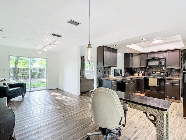 interior space featuring light hardwood / wood-style flooring, track lighting, black appliances, dark brown cabinets, and backsplash