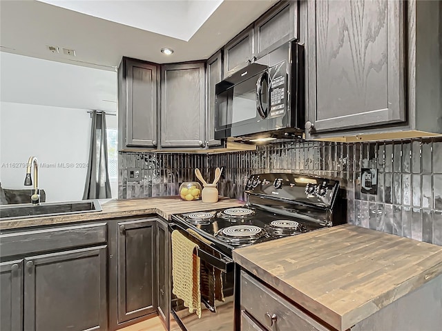 kitchen with light hardwood / wood-style flooring, tasteful backsplash, black appliances, sink, and dark brown cabinets