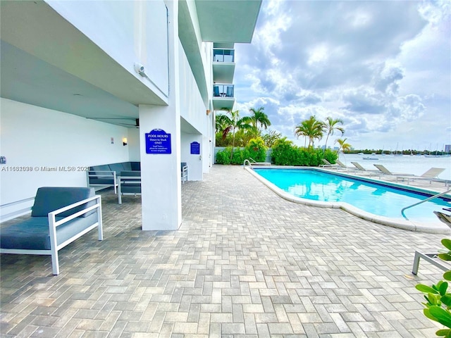 view of swimming pool with a patio area and a water view