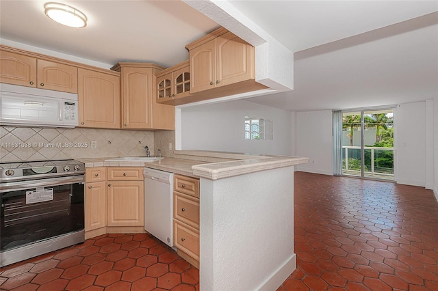 kitchen featuring white appliances, sink, decorative backsplash, light brown cabinetry, and kitchen peninsula