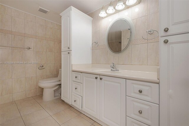 bathroom featuring tile patterned floors, vanity, toilet, and tile walls