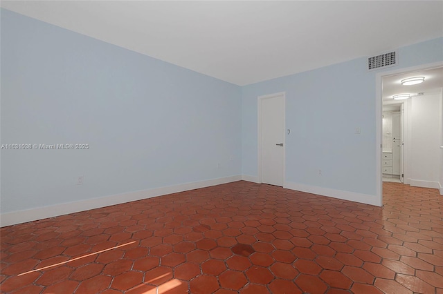 tiled empty room featuring baseboards and visible vents