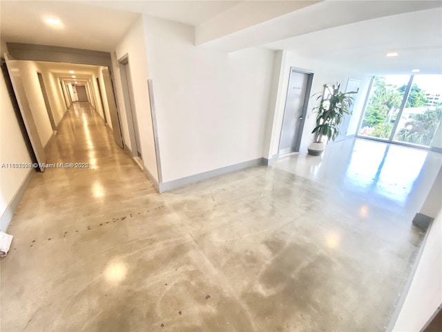 hallway with finished concrete flooring and baseboards