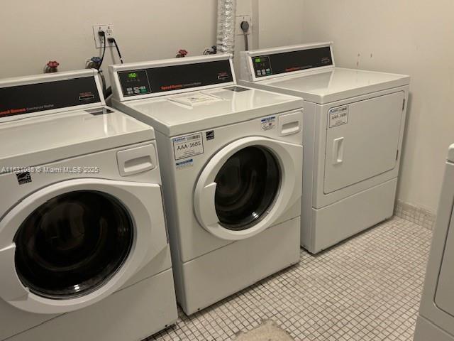 community laundry room with washer and dryer and light tile patterned floors