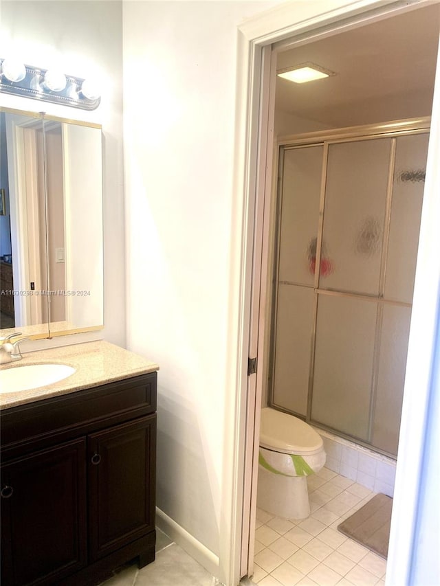 bathroom featuring baseboards, toilet, tile patterned floors, vanity, and a stall shower