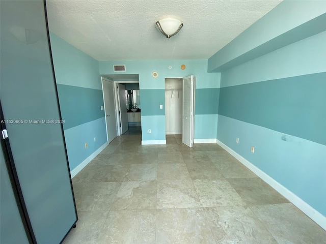 unfurnished bedroom featuring a textured ceiling and light tile patterned floors