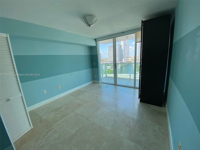 unfurnished room featuring tile patterned floors, a textured ceiling, and expansive windows