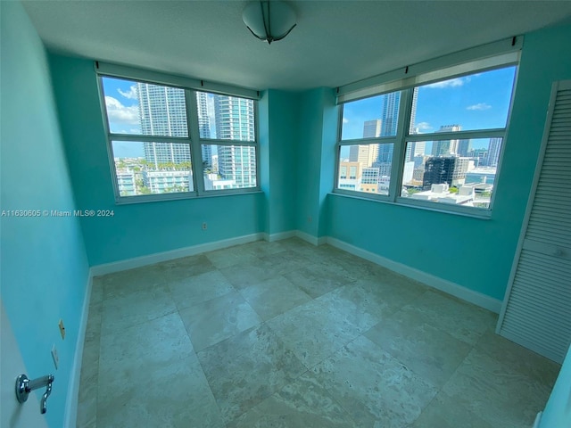 spare room with a wealth of natural light, a view of city, and baseboards