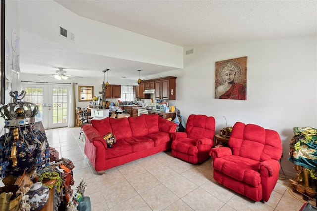 living area with lofted ceiling, french doors, light tile patterned floors, and visible vents