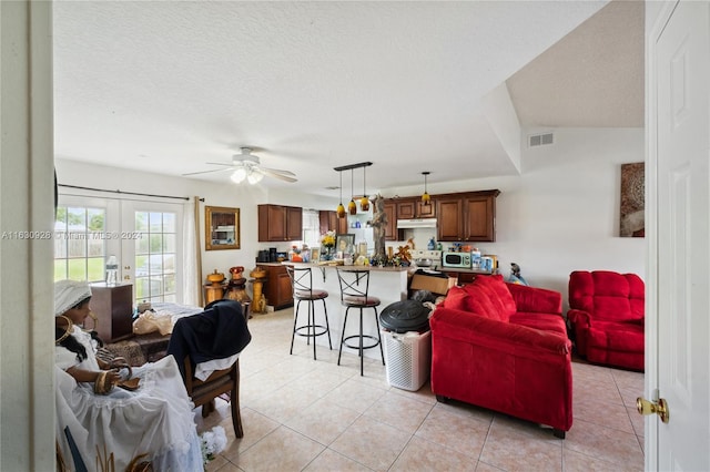 living area with light tile patterned floors, visible vents, a textured ceiling, and french doors