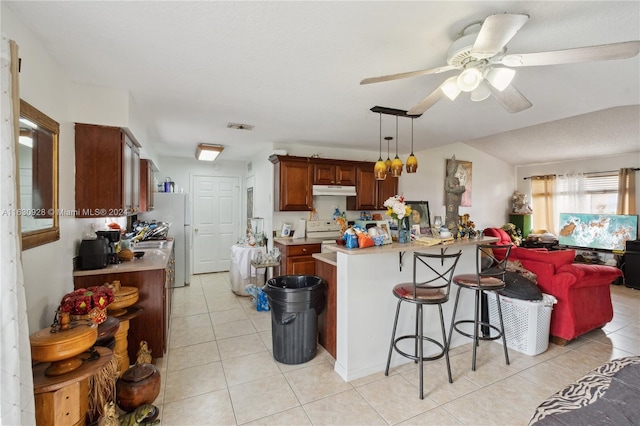 kitchen with a breakfast bar, visible vents, light countertops, and under cabinet range hood