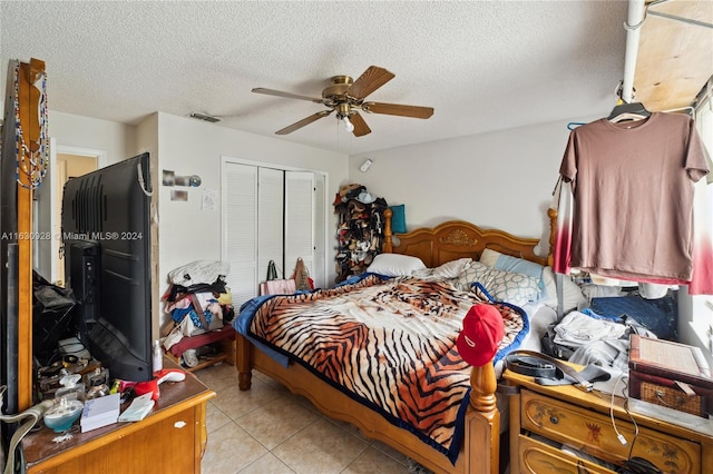 bedroom featuring light tile patterned floors, a closet, visible vents, ceiling fan, and a textured ceiling